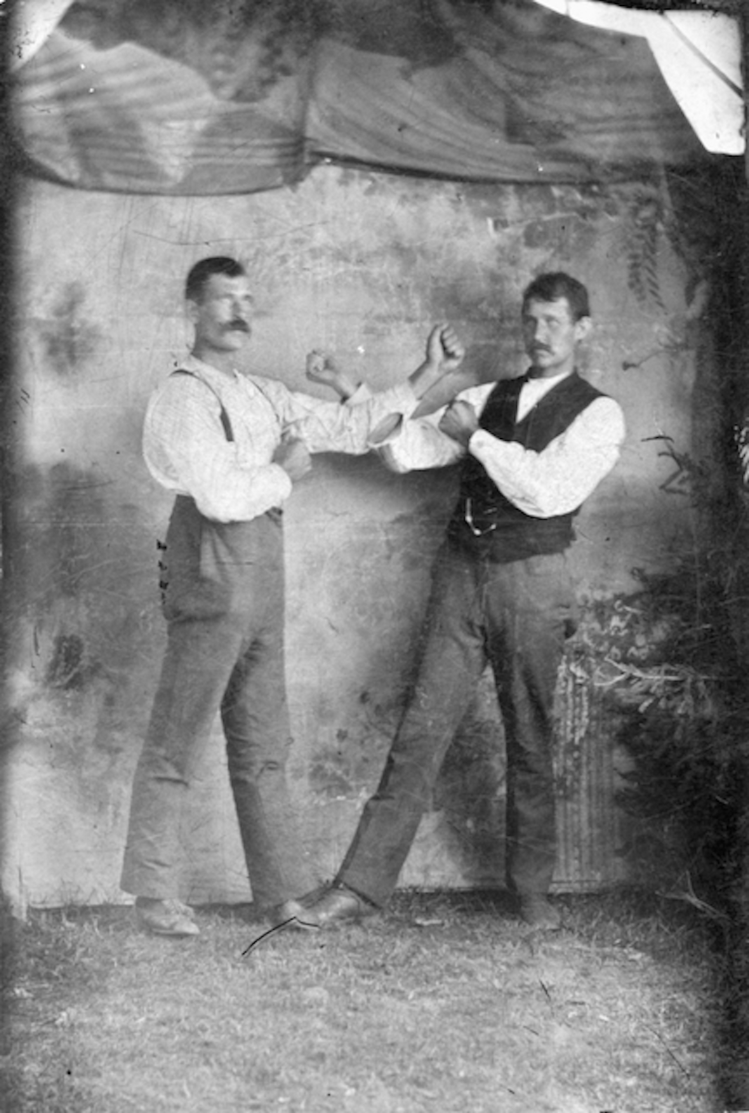 Knuckles Up! c1880s 2004.13.14 Even though Rat Portage was officially a town in 1881, it would have looked more like a work camp to the untrained eye. It was mostly occupied by young, single men who were here to work on the railway. During their down time these young men were always looking for things to do. One of the activities available in town at the time was having a picture taken. Young men would round up their pals and get a photo taken to send home or keep as a souvenir. The style of boxing pose in this photo was so common there is even a name for it: “The Fisticuffs Stance”. This stance became popular because it was used by fighters who fought under London Prize Ring Rules— the bareknuckle style of boxing that featured unlimited rounds, spiked shoes, and even some limited grappling. London Prize Ring Rules were banned in sanctioned matches in 1889 and were replaced with the Marquess of Queensberry Rules. These modern rules (mandatory gloves, 12-15 three minute rounds, standing eight count) made the traditional fisticuffs stance obsolete. A modern variation of the “fisticuffs pose”can sometimes be seen at MMA and boxing weigh-in events. Photographer unknown. From the collection of The Muse - Lake of the Woods Museum in Kenora, Ontario, Canada. Displayed as part of the exhibition, "Strike a Pose: Portraits from the Collection." November 17, 2020 - March 27, 2021.