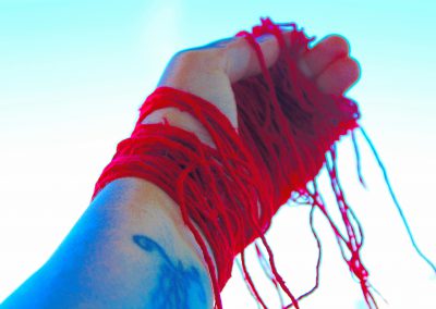 Image of a hand wrapped in red yarn.