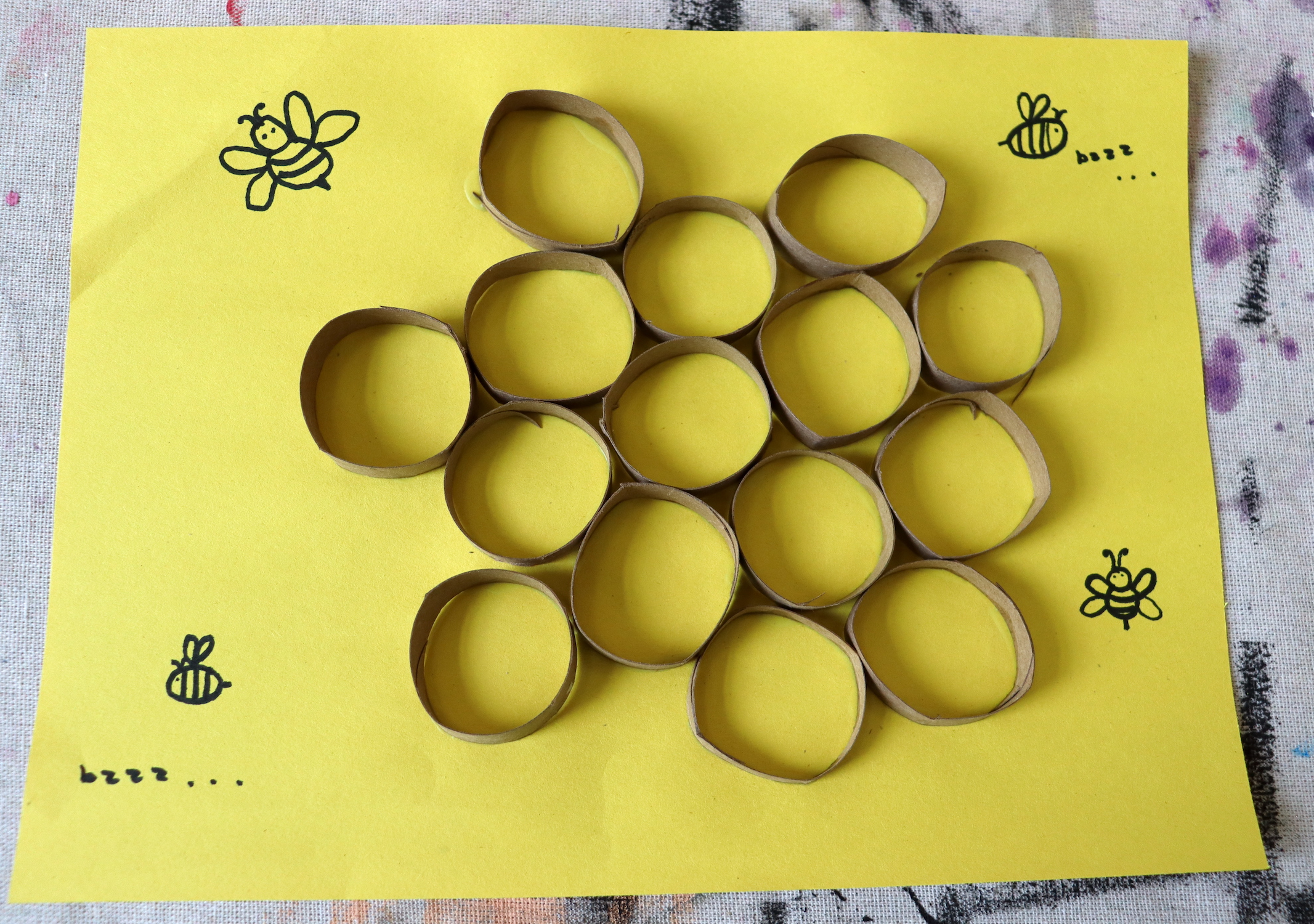 Photo depicting a paper roll honeycomb craft with drawings of bees.